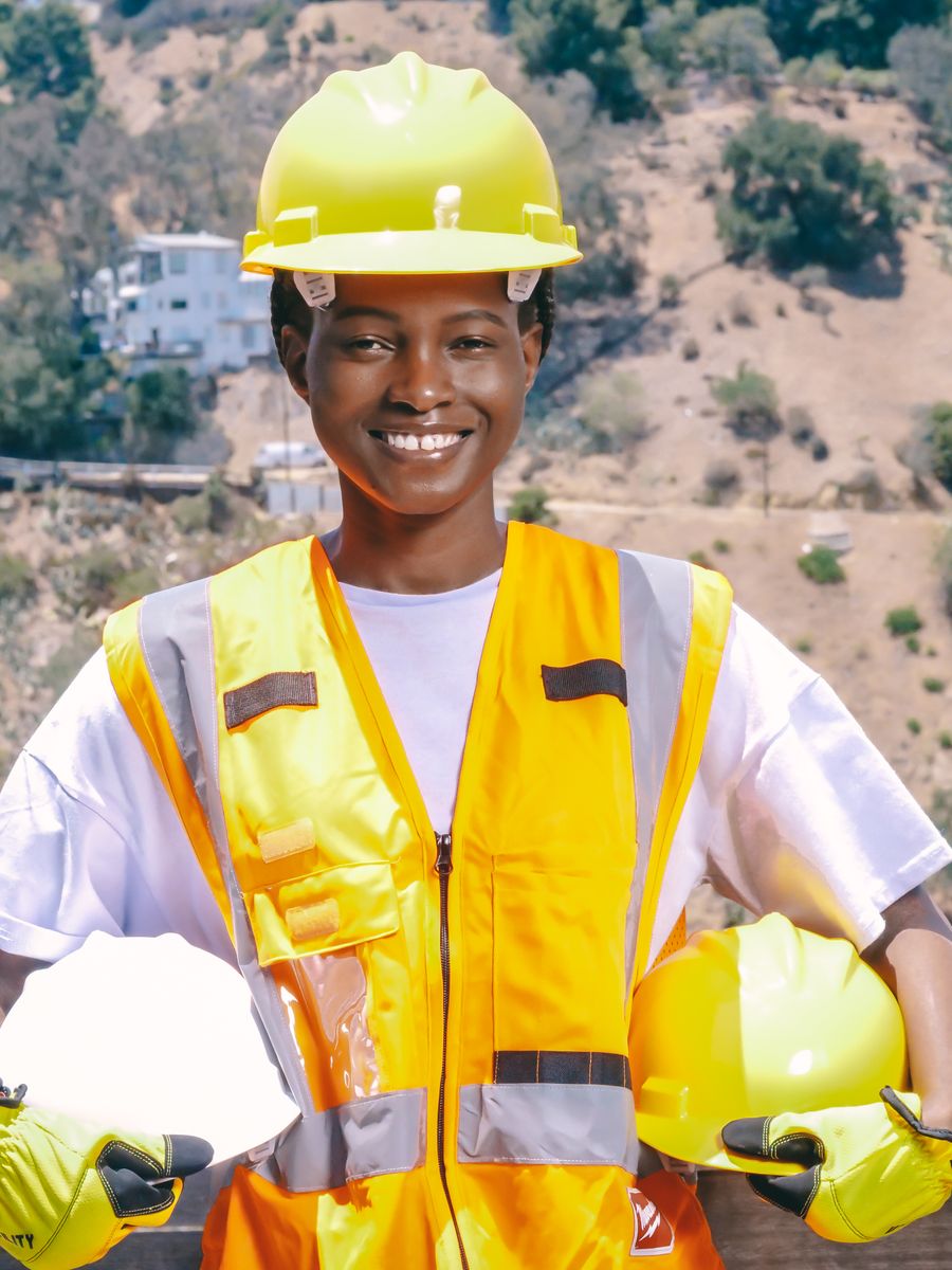 Engineer in a hard hat and hi-vis vest on site, holding a second helmet