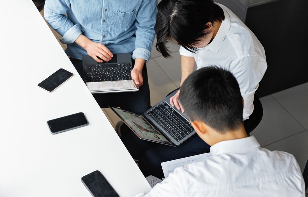 Colleagues working across laptops around a shared table, seen from above