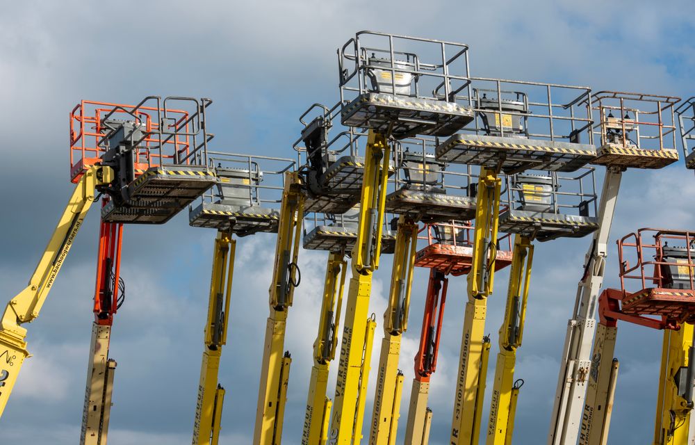 Fleet of access platforms with their booms raised against the sky