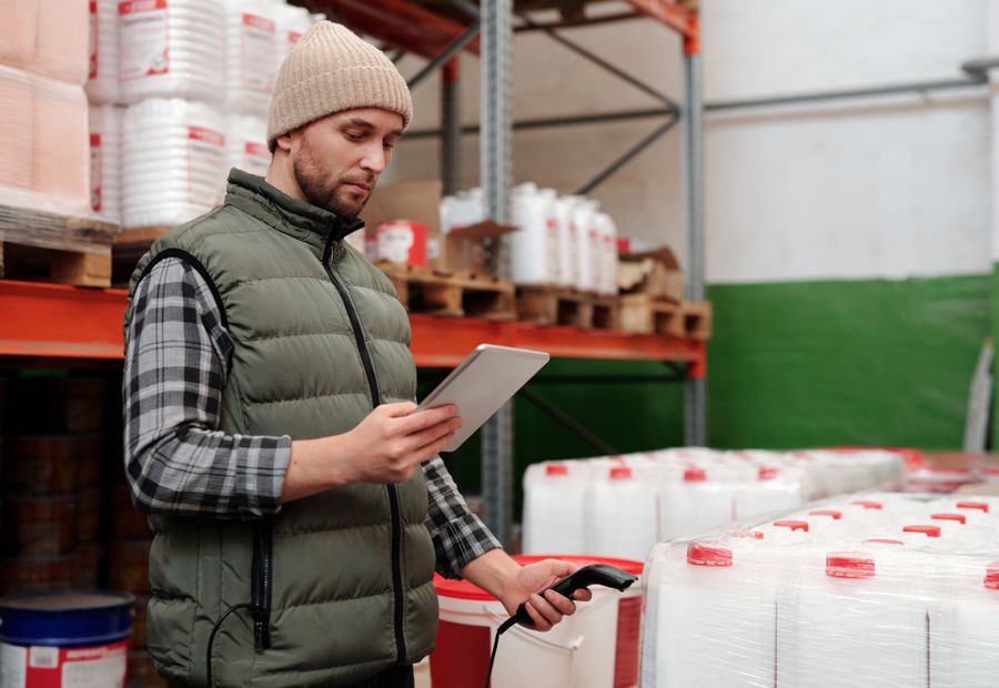 Warehouse staff member counting stock against a tablet