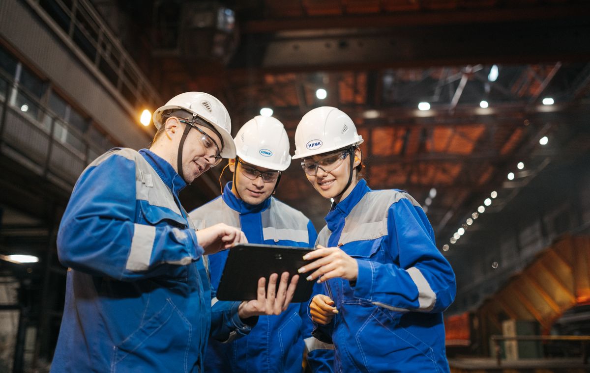 Group of engineers reviewing figures on a tablet on a factory floor