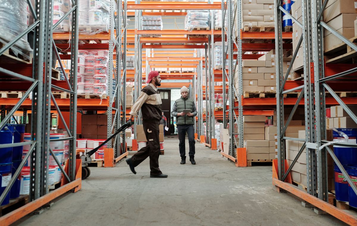 Two staff picking stock in a racked warehouse aisle